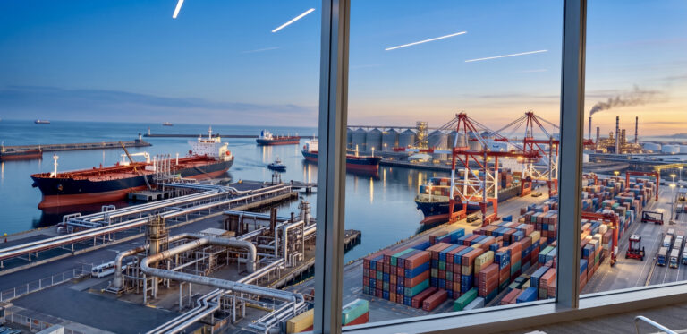 Global Sourcing and International Trade Operations An ultra-realistic view of a busy international commercial port with a bulk carrier ship and active logistics infrastructure, representing physical commodity sourcing and global trade operations.